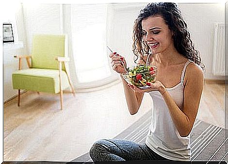 Woman eating a plate of salad.