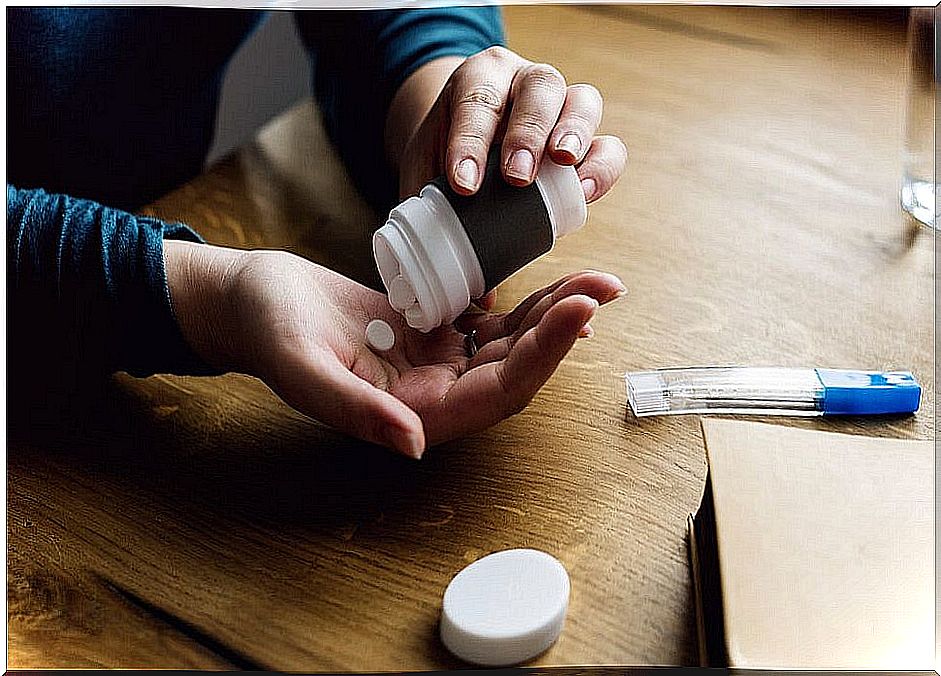 A person taking a pill from a painkiller bottle