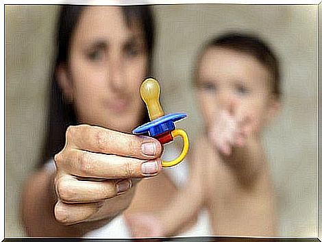 Mother with baby in her arms and pacifier in hand