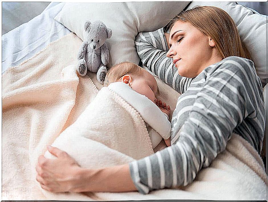 Mother sleeping with her baby in bed (co-sleeping).