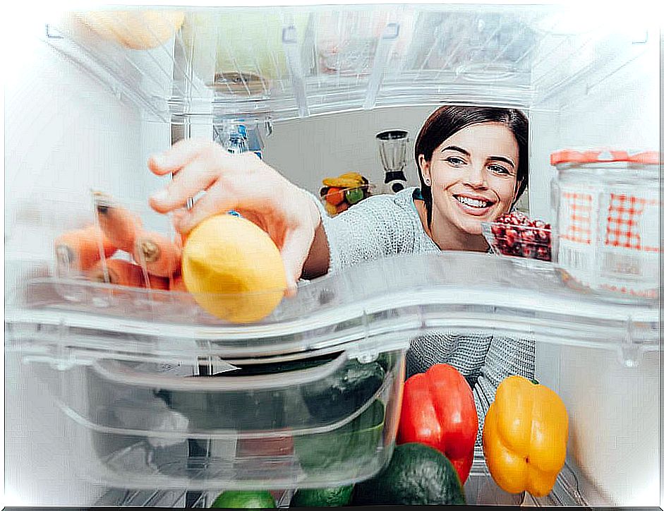 Woman taking a lemon from the refrigerator.