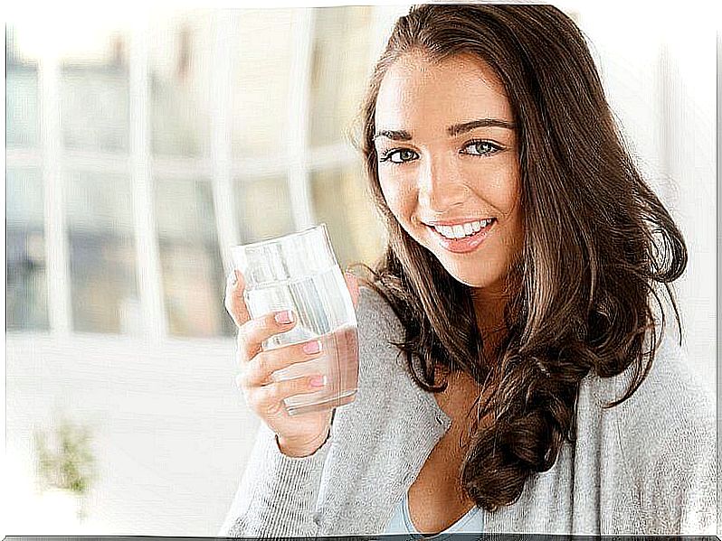 Woman with glass of water in hand depicting consuming water